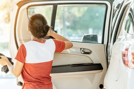 Woman cleaning with a blowers and microfiber wipe the car polishing after car wash.