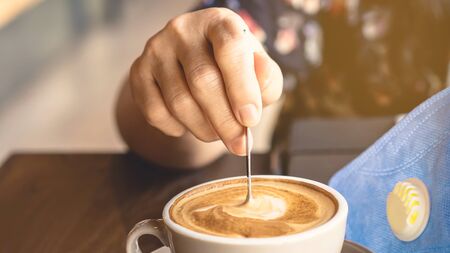 Woman with medical face mask drinking coffee in her house alone during corona virus or COVID-19 quarantine, Physical distancing for protect Covid-19 concept. Selective focus.の写真素材