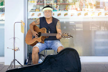 KANCHANABURI,THAILAND-APRIL 18,2020: Unidentified street musician wear a face mask playing guitar...