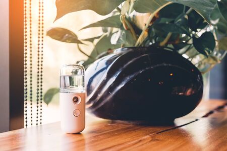 Alcohol nano mist sprayer for hand cleaning to prevent the spread of the corona virus (Covid-19) placed on the table to serve customers before buying in the coffee shop. Modern health technology.の写真素材
