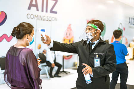 KANCHANABURI, THAILAND - APRIL 28,2020: Unidentified male officer use thermometer scan temperature for fever in people as coronavirus or COVID-19 outbreak at Robinson Department Store.のeditorial素材
