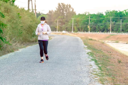 KANCHANABURI/THAILAND-MAY 7,2020 : Unidentified Thai sportive woman must wears protective mask on face jogging for good health due to the corona virus (Covid-19) outbreak at Mae Klong Dam.のeditorial素材