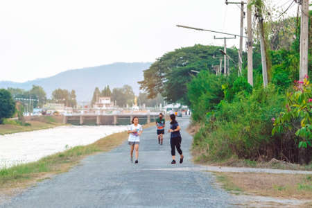 KANCHANABURI/THAILAND-MAY 7,2020 : Unidentified Thai sportive people jogging for good health on road beside irrigation canal at Mae Klong Dam on may 7,2020 in Kanchanaburi, Thailand.のeditorial素材