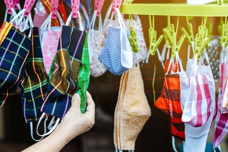 Close up to variety of colorful new face mask handmade sewing from fashion fabric cotton cloth for prevent germs (Covid-19) on sale at street market. Selective focus with blur in the background.の写真素材