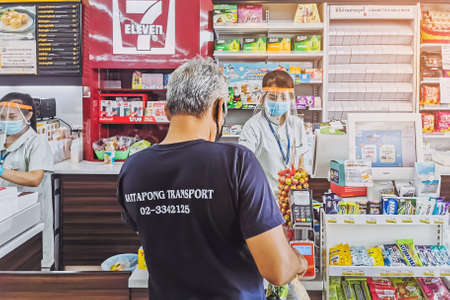 KANCHANABURI, THAILAND - APRIL 23,2020: Unidentified Cashier or 7-eleven staff and customers in medical protective mask to prevent the spread of corona virus (Covid-19) at 7-eleven on April 23,2020のeditorial素材