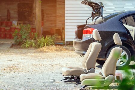 Cream-colored car seats removed from the black car for sun exposure and cleaning in open air.の写真素材