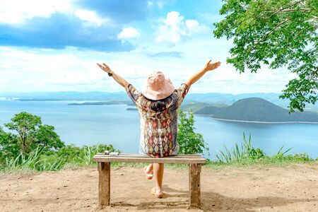 Back view of woman enjoy with beautiful scenery view of nature with a large reservoir above the Srinagarind Dam at Rai Ya Yam view point in Si Sawat District, Kanchanaburi Thailand.の写真素材