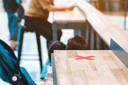 Female elementary school student wear face mask to prevent the Coronavirus(Covid-19) wait for her parents to pick her up to return home after school and the rain just stop in front of the school gateの写真素材