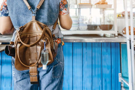 Mini portable alcohol gel bottle to kill Corona Virus(Covid-19) hang on a leather shoulder bag of a...
