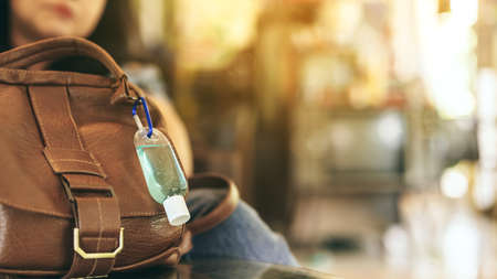 Mini portable alcohol gel bottle to kill Corona Virus(Covid-19) hang on a leather shoulder bag of a...