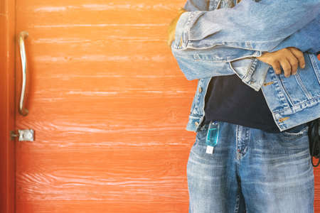 Mini alcohol gel bottle to kill Corona Virus(Covid-19) hang on a brown leather shoulder bag with hot coffee on table in cafe.New normal lifestyle.Health care concept.Selective focus on alcohol gelの写真素材