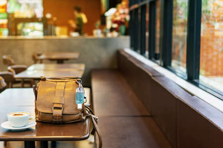 Mini alcohol gel bottle to kill Corona Virus(Covid-19) hang on a brown leather shoulder bag with hot...