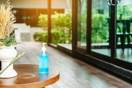Blue alcohol gel bottle for hand cleaning to prevent the spreading of the Coronavirus (Covid-19) to service for customers placed on table in front of cafe. Healthcare concept. New normal lifestyleの写真素材