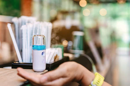 Alcohol nano mist sprayer for hand cleaning to prevent the spread of the Corona virus (Covid-19) to serve customers at coffee shop. Modern health technology. New normal lifestyle. Selective focusの写真素材
