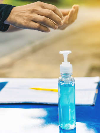 Mini portable alcohol gel bottle to kill Corona Virus(Covid-19) hang on a leather shoulder bag of a woman wearing a mask to shopping in supermarket.New normal lifestyle.Selective focus on alcohol gelの写真素材