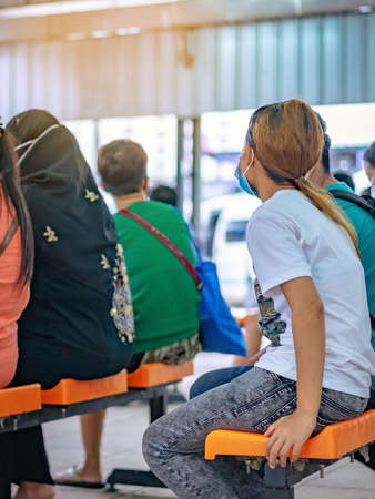 Male tourist prepare to carry luggage and surgical mask to prevent Corona Virus(Covid-19) to travel by public transport at transport station. New normal lifestyle, Selective focus on surgical mask.の写真素材
