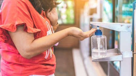 Hands of woman pressed blue alcohol gel bottle to prevent the spreading of the Coronavirus...