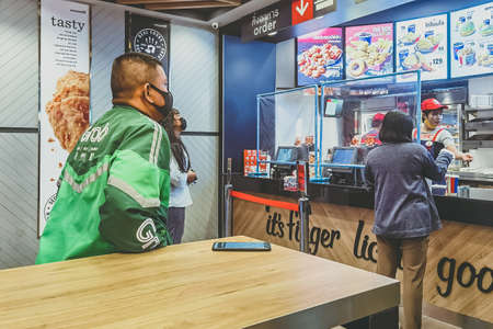KANCHANABURI ,THAILAND-AUGUST 23, 2020:Unidentified Grab rider wear protective face mask to prevent Coronavirus (Covid-19) queueing to ordering food at Kentucky Fried Chicken (KFC) in PTT gas station.のeditorial素材