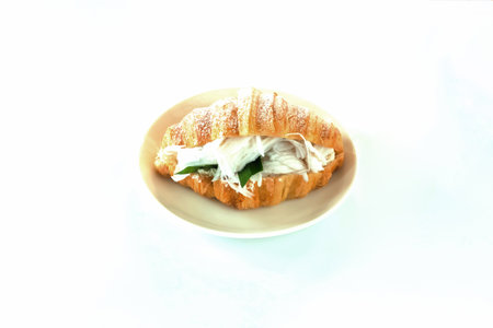 Freshly baked croissant stuffed with fresh coconut on white plate. Croissant sandwich with coconut, homemade isolate with white background. French pastry. traditional French breakfast.の写真素材