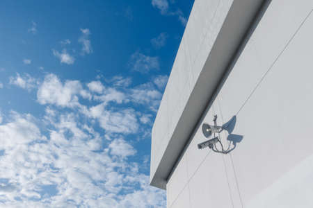 Loudspeakers and CCTV security cameras observation on a wall of a buildingの写真素材