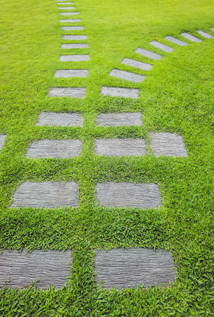 Walkway sheet stretching into the distance with green grass lawn in perspective view in garden. Garden landscape design concept, A row of square-shaped walkways in the public park.の写真素材