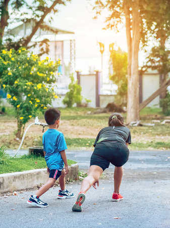 Back view of sportive happy mother training her son doing stretching before exercise in garden. Athletic family exercising together outdoor. Kid care exercise sport activity conceptの写真素材