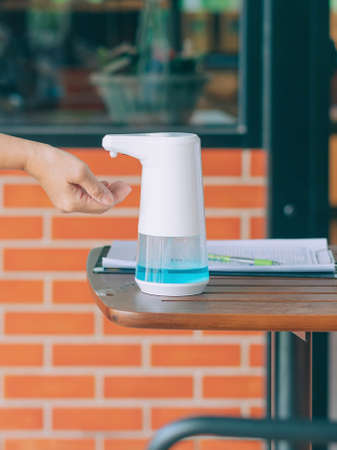 Automatic alcohol dispenser for cleaning hand to prevent the spreading of  virus  on table before entrance to cafeteria. Healthcare concept. New normal lifestyle. Selective focusの写真素材