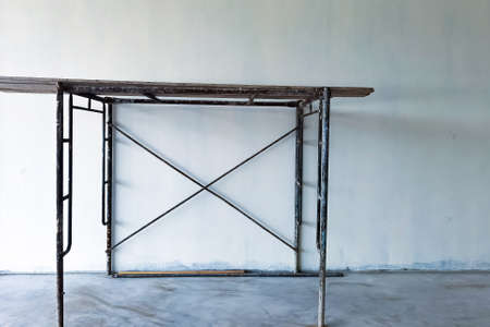 Provide scaffolding for Interior construction and painting of warehouse concrete wall.Empty white room with scaffolding. Old house during renovation. Old scaffolding inside of house construction site.の写真素材