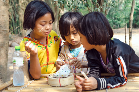 RATCHABURI THAILAND-JANUARY 19,2020 : Unidentified happiness Karen young girls in tribal costumes are counting coins and sharing the proceeds from the sale with their friends equally at Ohpoi Market.のeditorial素材
