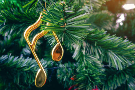 Shiny treble clef ornament or gold music notes hanging on pine tree. Stylish christmas decorations. Christmas and New Year display for celebration,carnival,festival design concept. Selective focus.の写真素材