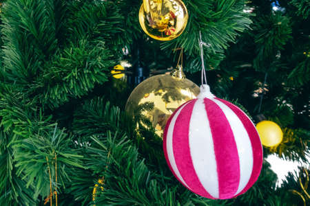 Pink and white Christmas fabric ball hanging on artificial pine tree. Stylish christmas decorations. Christmas and New Year display for celebration,carnival,festival design concept. Selective focus.の写真素材
