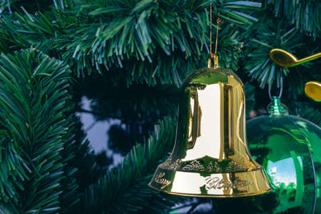 Golden jingle bells christmas ornament hanging on artificial pine tree. Stylish christmas decorations. Christmas and New Year display for celebration,carnival,festival design concept. Selective focus.の写真素材