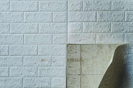 The wallpaper begins to peel off. Old white bricks wallpaper peeled off from the wall inside the...