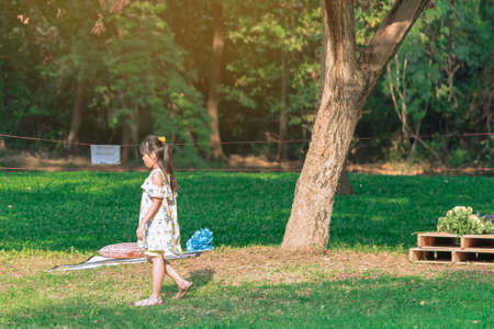 KANCHANABURI, THAILAND-JANUARY 11,2020 : Happiness Asian young girl having fun alone on lawn through green garden among trees and green grass at Mulberry Mellow (Open air coffee shop).のeditorial素材
