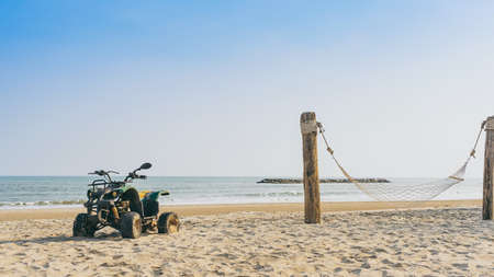 Vintage green ATV on the sandy beach. Quad ATV all terrain vehicle parked on beach, Motor bikes ready for action with summer sun flaring on bright day. Outdoor extreme activity adrenaline sport.の写真素材
