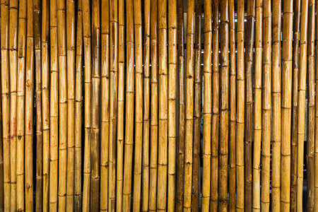 Old brown tone bamboo simple wall or Bamboo fence texture background for interior or exterior design vintage tone. Brown bamboo stick pattern backdrop. Local area urban house protection from thief.の写真素材