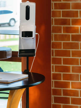 Stand automatic alcohol dispenser spraying with automatic body thermometer check temperature for covid-19 pandemic for safety before entering the coffee shop. Equipment to control and kill virus.の写真素材