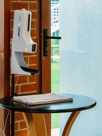 Stand automatic alcohol dispenser spraying with automatic body thermometer check temperature for covid-19 pandemic for safety before entering the coffee shop. Equipment to control and kill virus.の写真素材