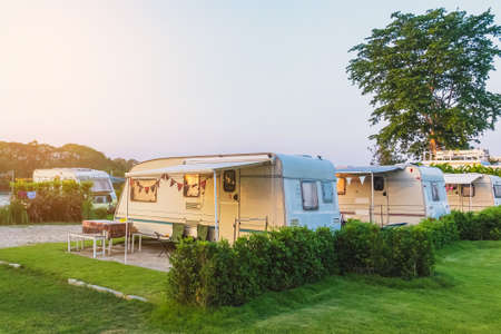 Cozy retro travel trailer Caravan on green grass before sunset near riverside in peaceful countryside. Family vacation travel RV, holiday trip in motorhome. Outdoor and Recreational Vehicles Theme.の写真素材