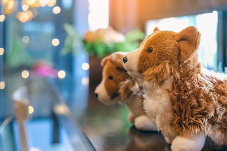 Cute white and brown dogs doll sit on counter near large glass window in coffee shop. Lovely animal toys decoration in cafe. Beautiful doll dogs in brown and white colour with lot of fur. Fluffy toys.の写真素材