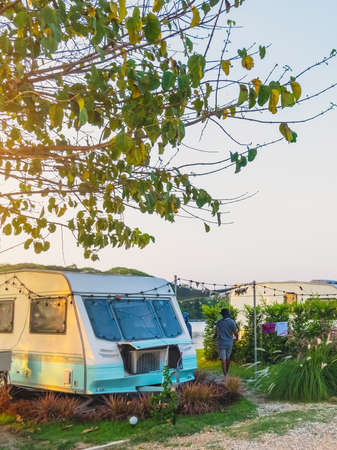Cozy retro travel trailer Caravan on green grass before sunset near riverside in peaceful countryside. Family vacation travel RV, holiday trip in motorhome. Outdoor and Recreational Vehicles Theme.の写真素材