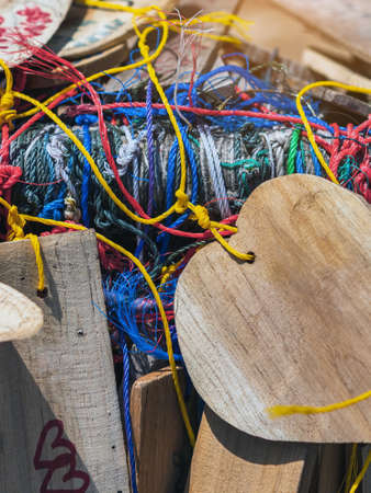 Many suspended chaotically intertwined colorful ropes tied into messy knots for plate wood hanging on rail of traditional. A lot of wooden tags hangs with colorful ropes. Selective focus.の写真素材
