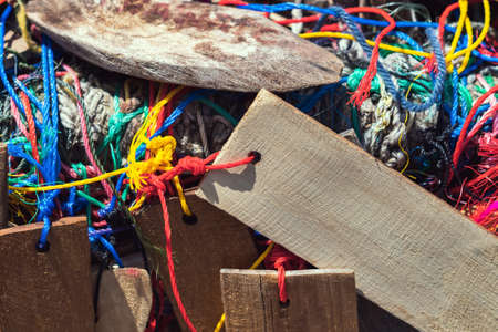 Many suspended chaotically intertwined colorful ropes tied into messy knots for plate wood hanging on rail of traditional. A lot of wooden tags hangs with colorful ropes. Selective focus.の写真素材