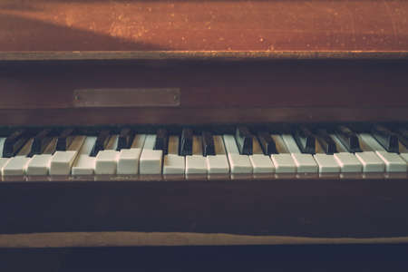 Close up shot to broken piano keys in abandoned house. An ancient musical instrument. Old broken disused piano with damaged keys Vintage Retro Filter. Distressed Piano made of wood. Selective Focus.の写真素材