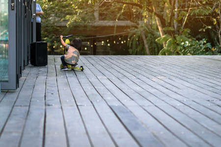 Asian kid enjoy playing and riding scooter without using any safety gear in home. Active lifestyle of children in nature. Happy little boy ride scooter without helmet. Active sport for preschool kid.の写真素材