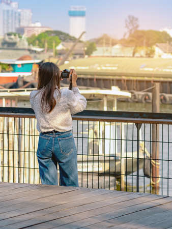 Back view portrait of attractive Asian woman photographer or traveller using a professional...