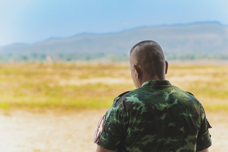 Back view of Asian army soldier stands to explore the landscape in field. Command class soldier...