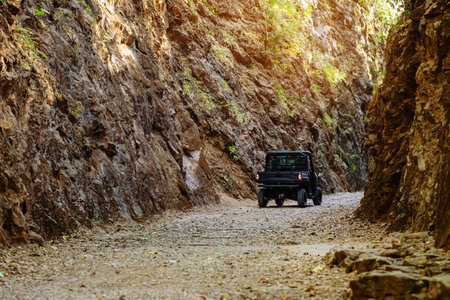 Tourist SUV car cruising along a rugged route through the gorge that was once a former railway line built by prisoners of war during the World War 2 at Hellfire Pass in Kanchanaburi Province,Thailand.の写真素材