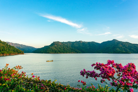 VIew of long-tailed boat floating on blue river in mountain with green forest. River in Khun Dan Prakan Chon Dam in Thailand. Landscape. Tourists on a boat to enjoy scenery in evening. Tourism conceptの写真素材