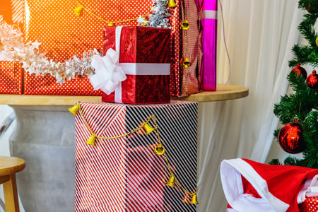 Colorful Christmas gift boxes with ribbon and Christmas decorations on table in house to celebrate New Year and Christmas season. Beautiful holiday decorated room with gift boxes and Christmas tree.の写真素材